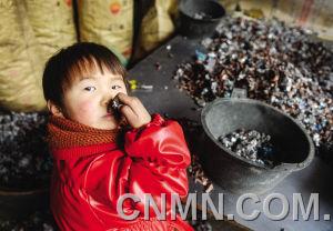 个小朋友在台州市路桥区峰江街道一家拆解小作坊内玩分拣出来的金属。